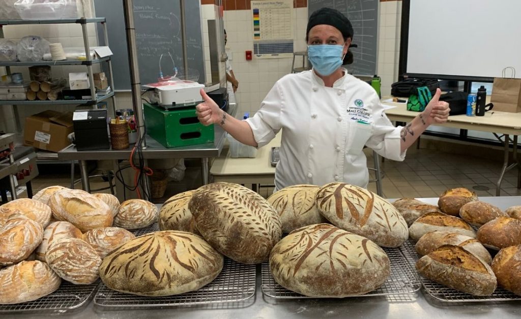 Student Baker Amber Kalish poses by bread donated to Hungry Homeless Heroes